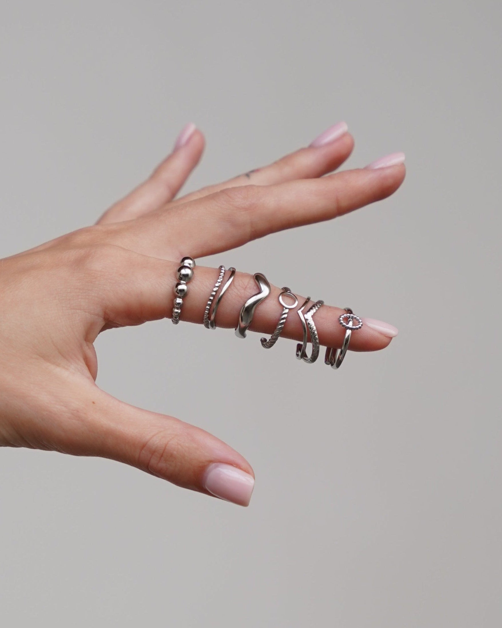 handmodel met 6 verschillende zilverkleurige ringen om vinger