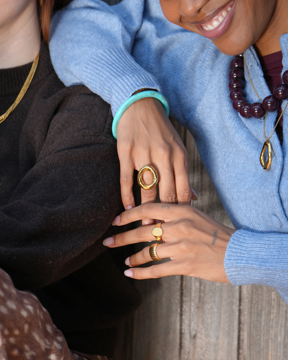 Jhene ring, goudkleurige statement ring met een grote open ovale vorm in een organisch, golvend design, gedragen om de middelvinger.