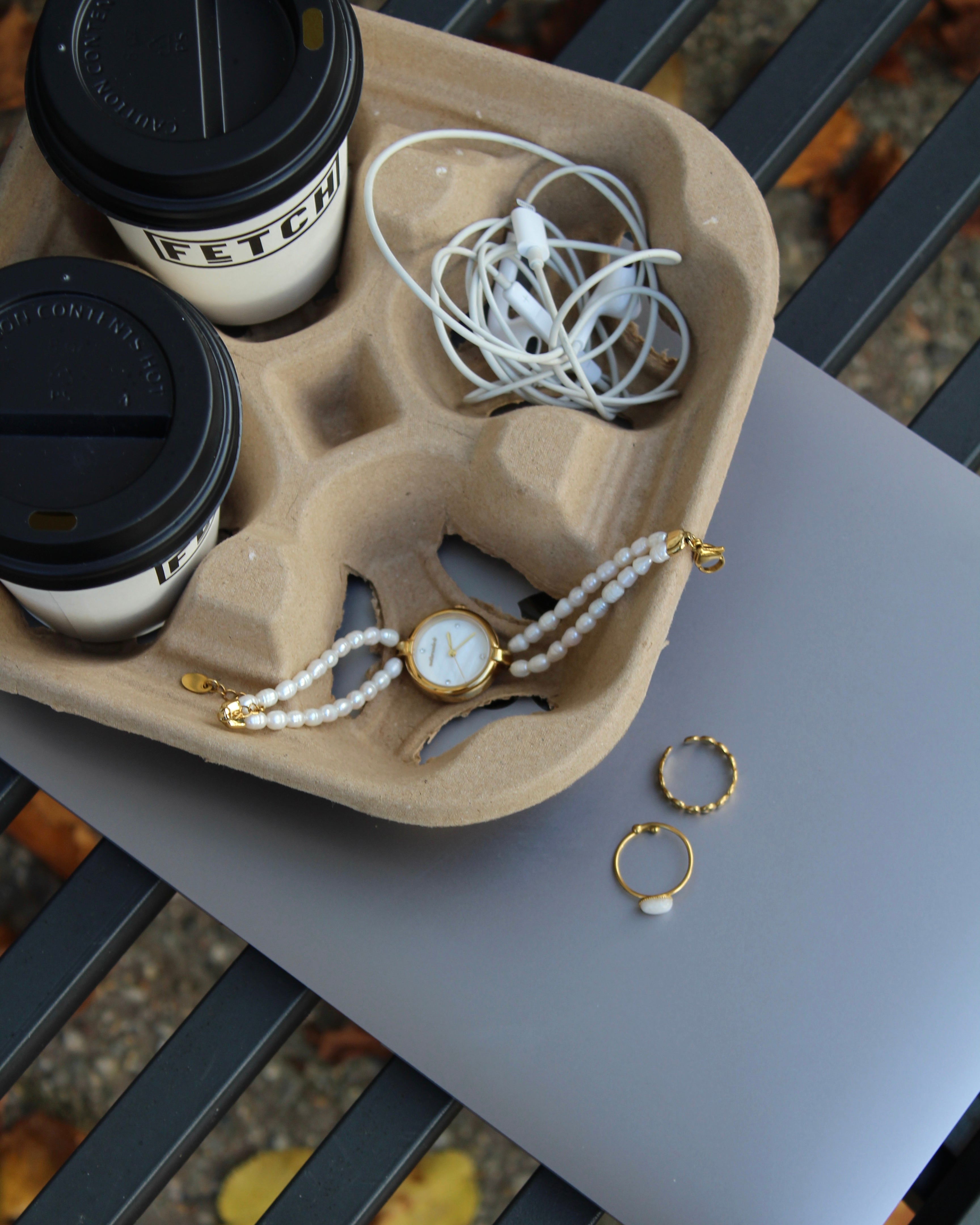 horloge met een parel band op een bankje met een laptop en koffie