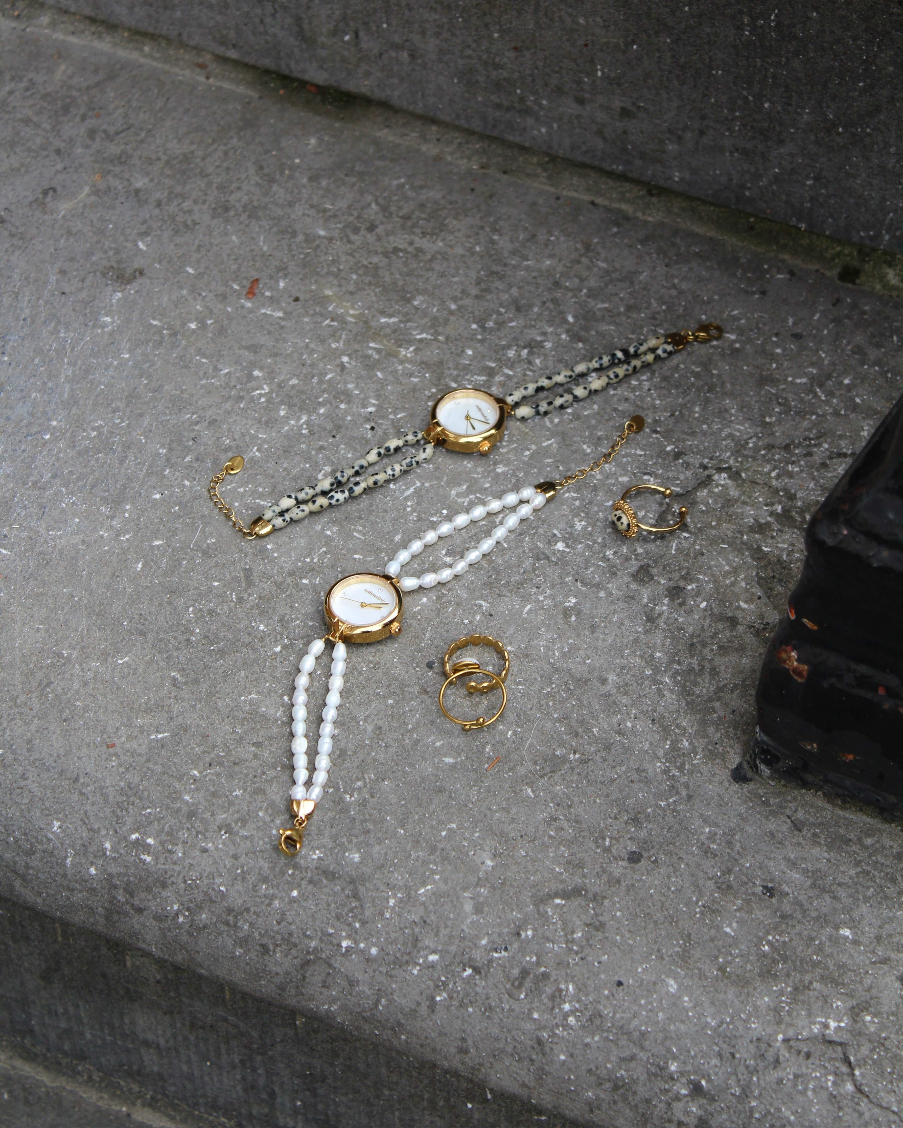2 horloges die op een steen liggen met ringen